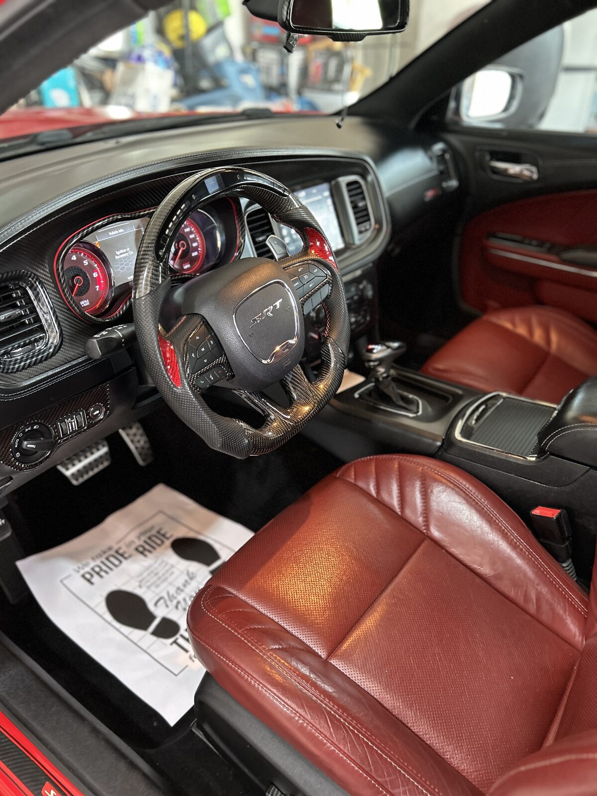 Carbon fiber interior of a Dodge Charger SRT after a Top Auto Detailing full detail, with red leather seats and freshly conditioned dash